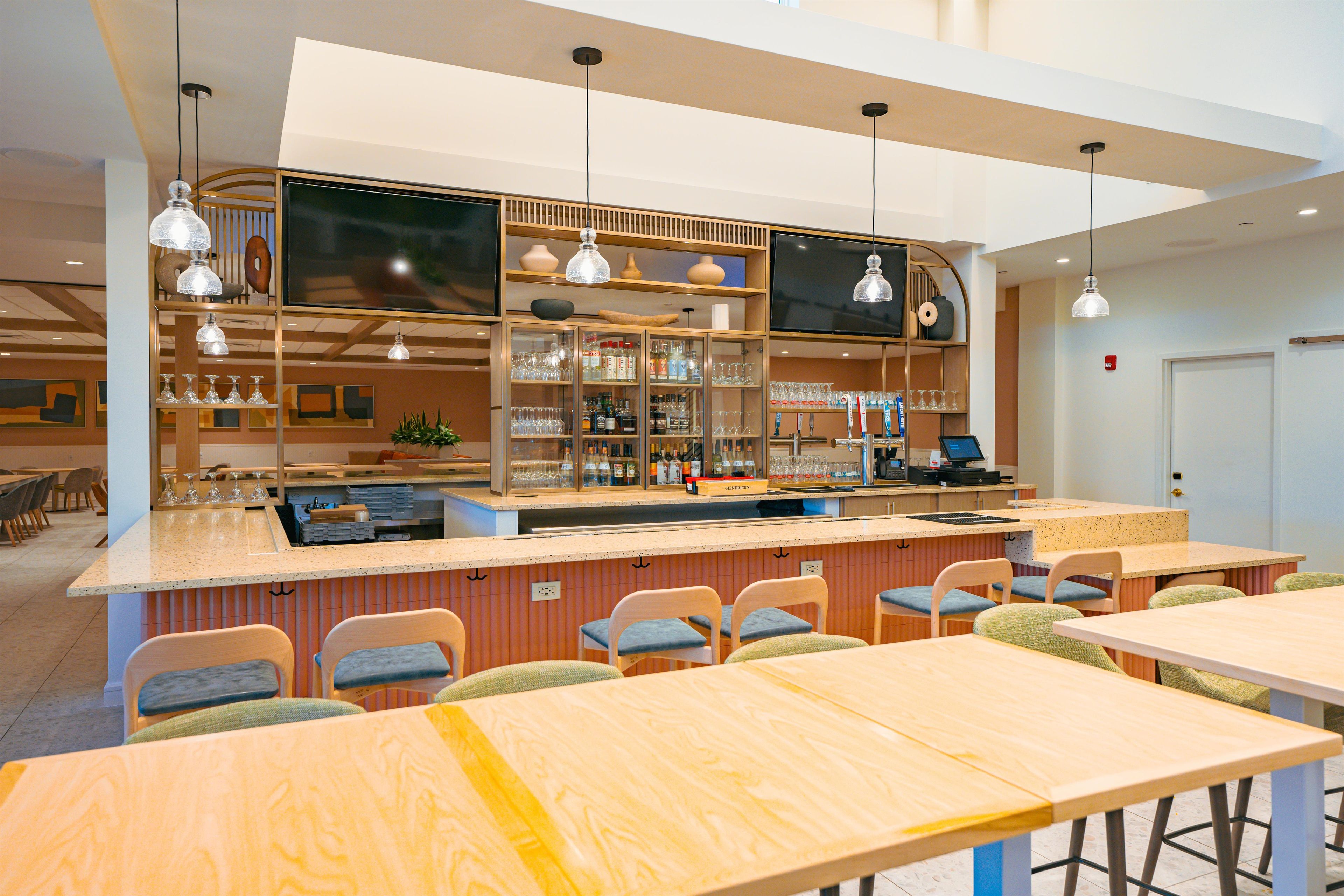 A bar area with seating and a counter, featuring glassware and bottles.