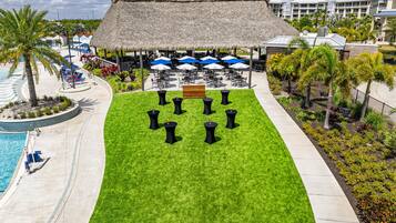 A resort with a pool, outdoor seating area, and a thatched-roof structure.