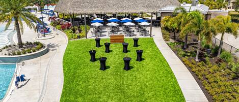 A resort with a pool, outdoor seating area, and a thatched-roof structure.