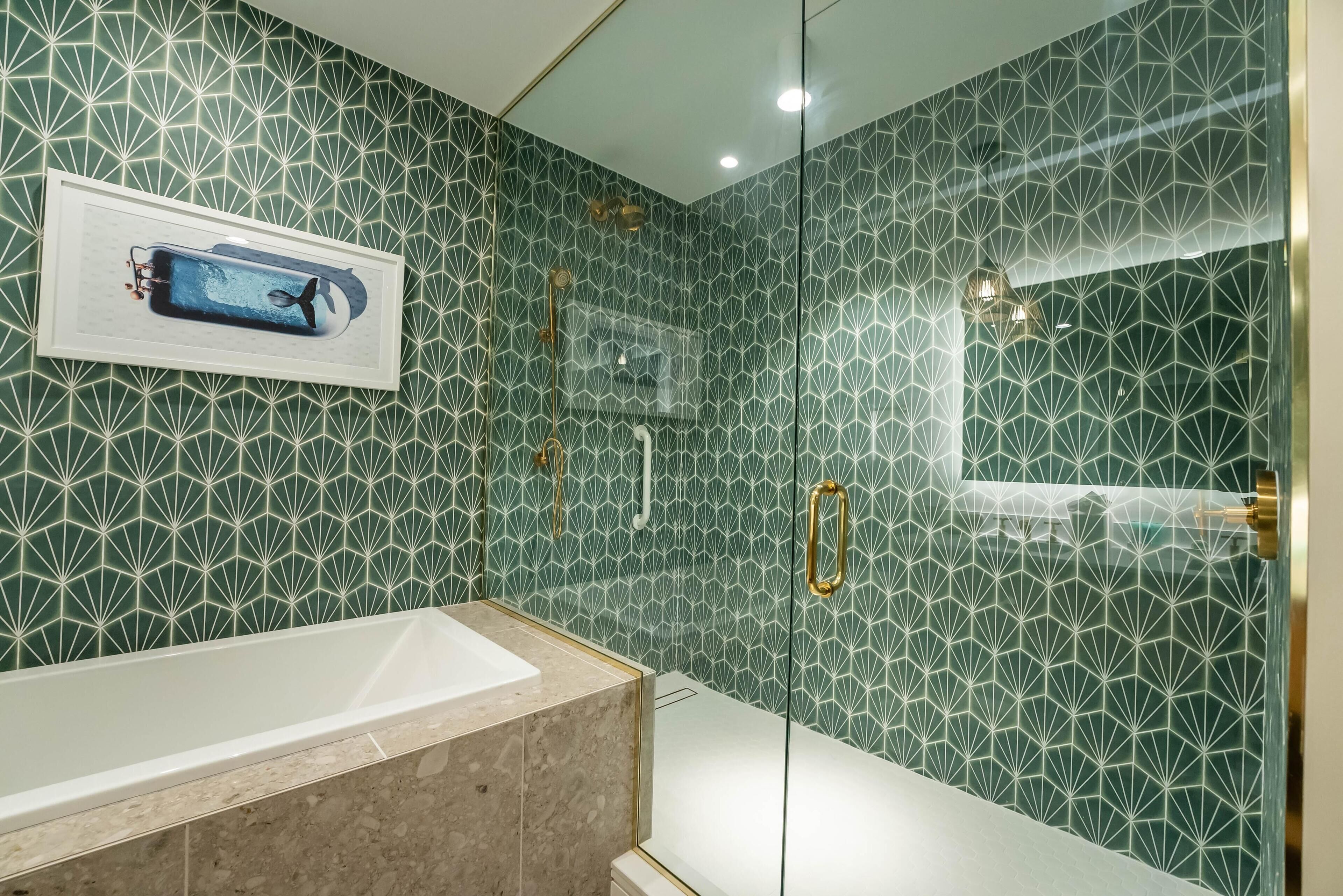 Un baño con ducha envuelta en vidrio, bañera y pared con diseño.