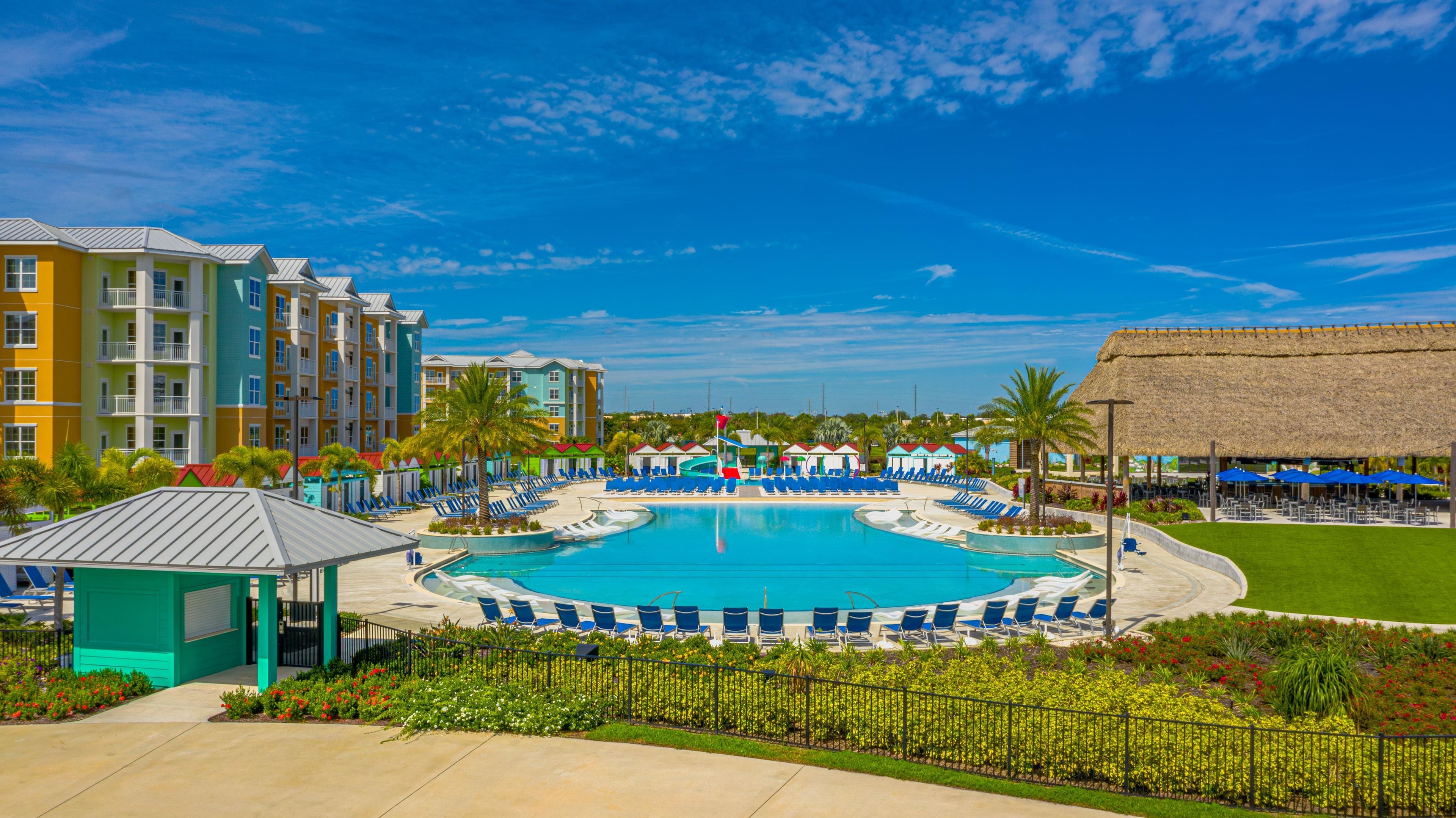 A resort with a central swimming pool, multiple lounge areas, and colorful buildings.
