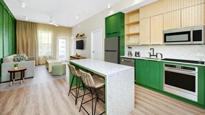 Une cuisine moderne avec des meubles de couleur verte, un plan de travail blanc et un four encastré.