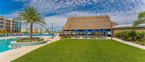 Un complexe hôtelier doté d’une piscine, d’une structure à toit de chaume et d’une pelouse.
