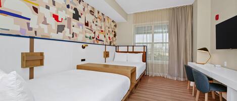 A hotel room with two single beds, a desk, and a chair.