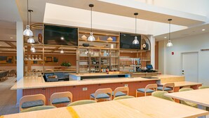 A modern bar area with seating, a counter, and shelves with glassware and bottles. - Embassy Suites By Hilton Orlando Sunset Walk (Kissimmee)