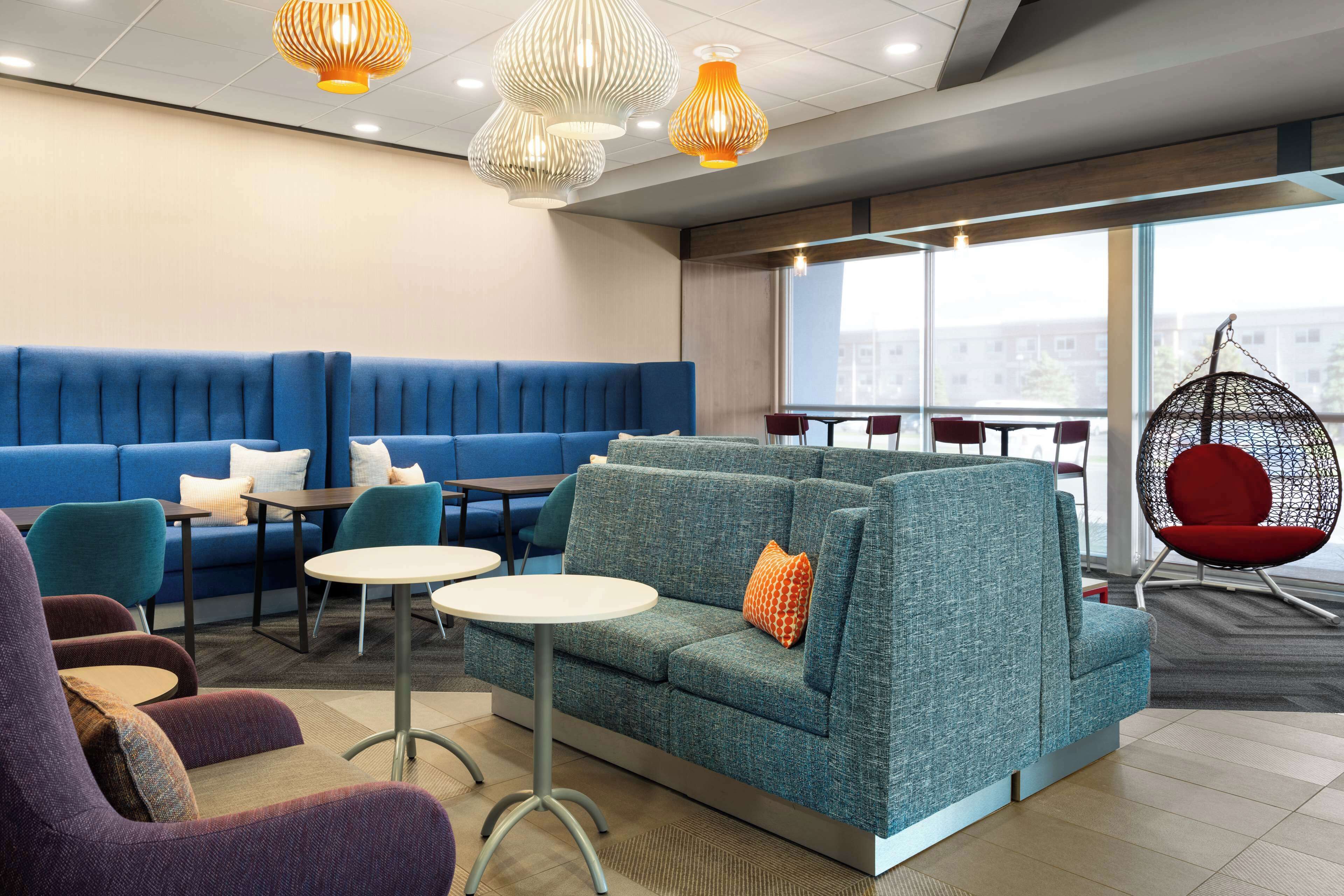 A modern lounge area with seating arrangements, including sofas and chairs, and a hanging chair.