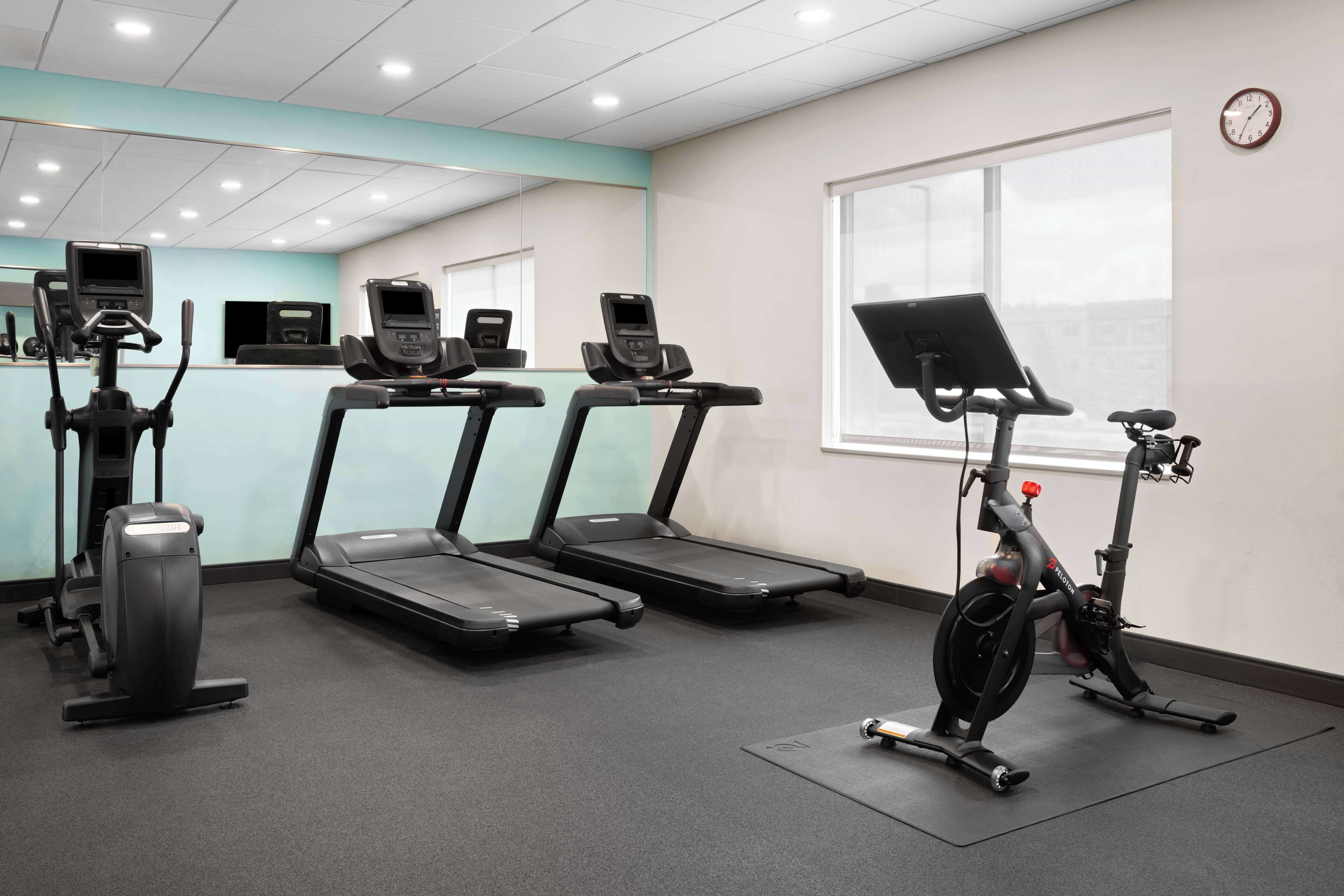 Un gimnasio con cintas de correr, elípticas y una bicicleta estática.