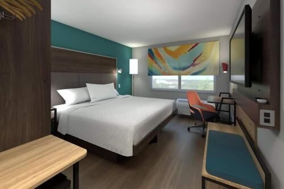 A modern hotel room with a large bed, a desk, and a TV.