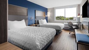 Une chambre d’hôtel avec deux lits, un bureau et une télévision.