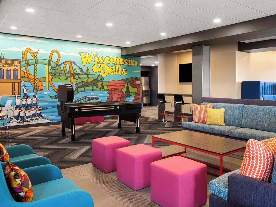 Un hall d’hôtel agrémenté de sièges aux couleurs vives, d’un piano et d’une fresque représentant les chutes du Wisconsin Dells.