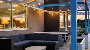 Un espace extérieur aménagé avec un canapé d’angle, une table ronde et des guirlandes lumineuses.