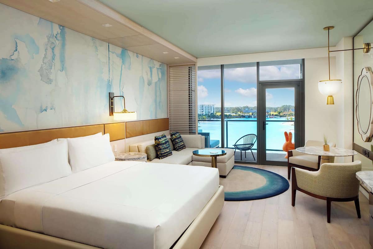 Une chambre d’hôtel avec un grand lit, un canapé, une petite table ronde et une vue sur la mer.