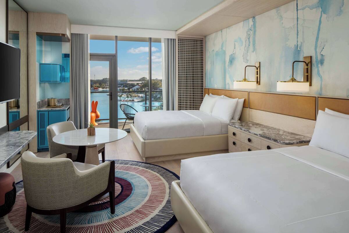 Une chambre d’hôtel avec un grand lit, un bureau, une chaise et une vue sur une étendue d’eau.