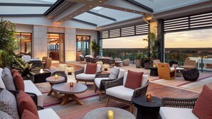 Eine Dachterrasse mit Korbmöbeln, runden Tischen und Topfpflanzen.