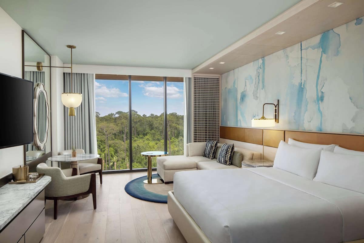 Une chambre d’hôtel moderne dotée d’un grand lit, d’un canapé, d’un coin repas et d’une télévision.