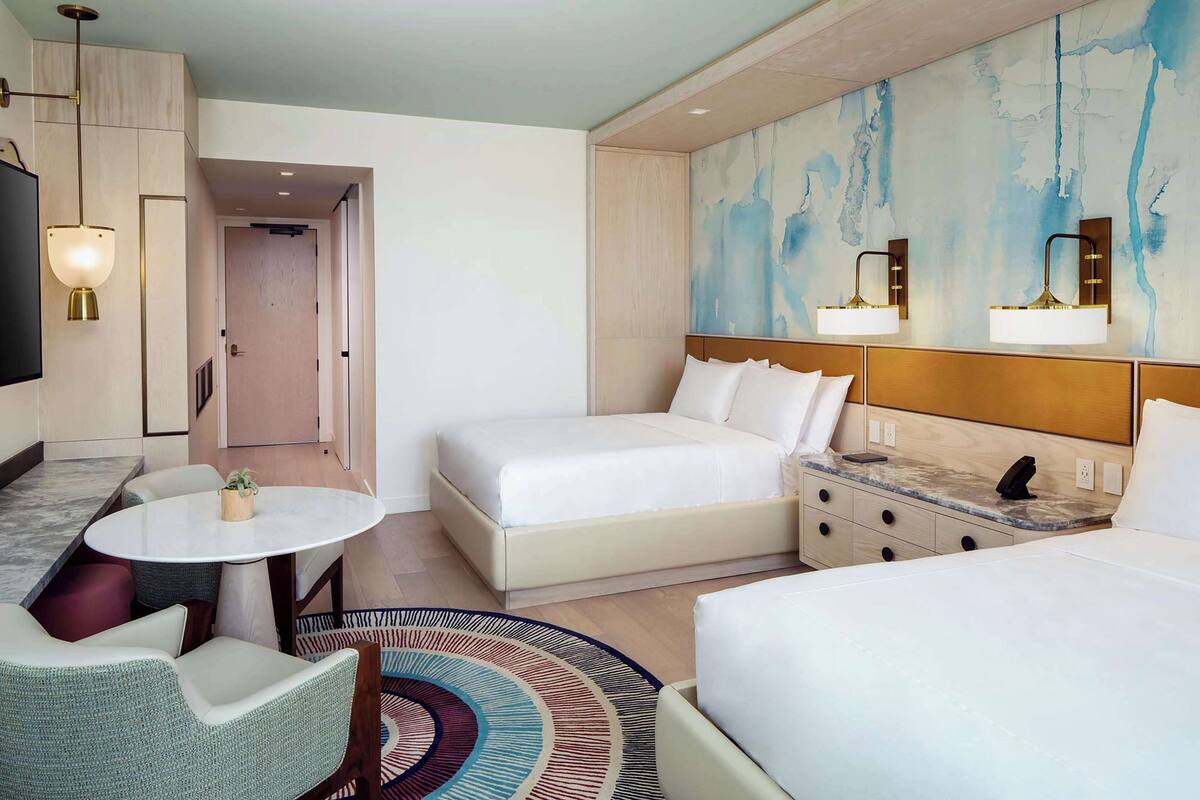 Une chambre d’hôtel avec un grand lit, un bureau avec une chaise, une petite table ronde et un téléviseur.