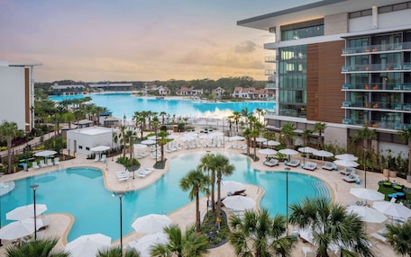 A resort with multiple swimming pools, lounge areas, and a modern building with balconies.