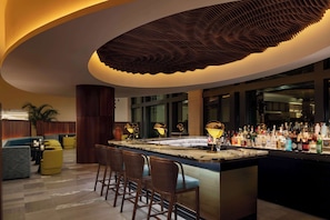 A bar area with a curved ceiling, bar stools, and a well-stocked bar counter.