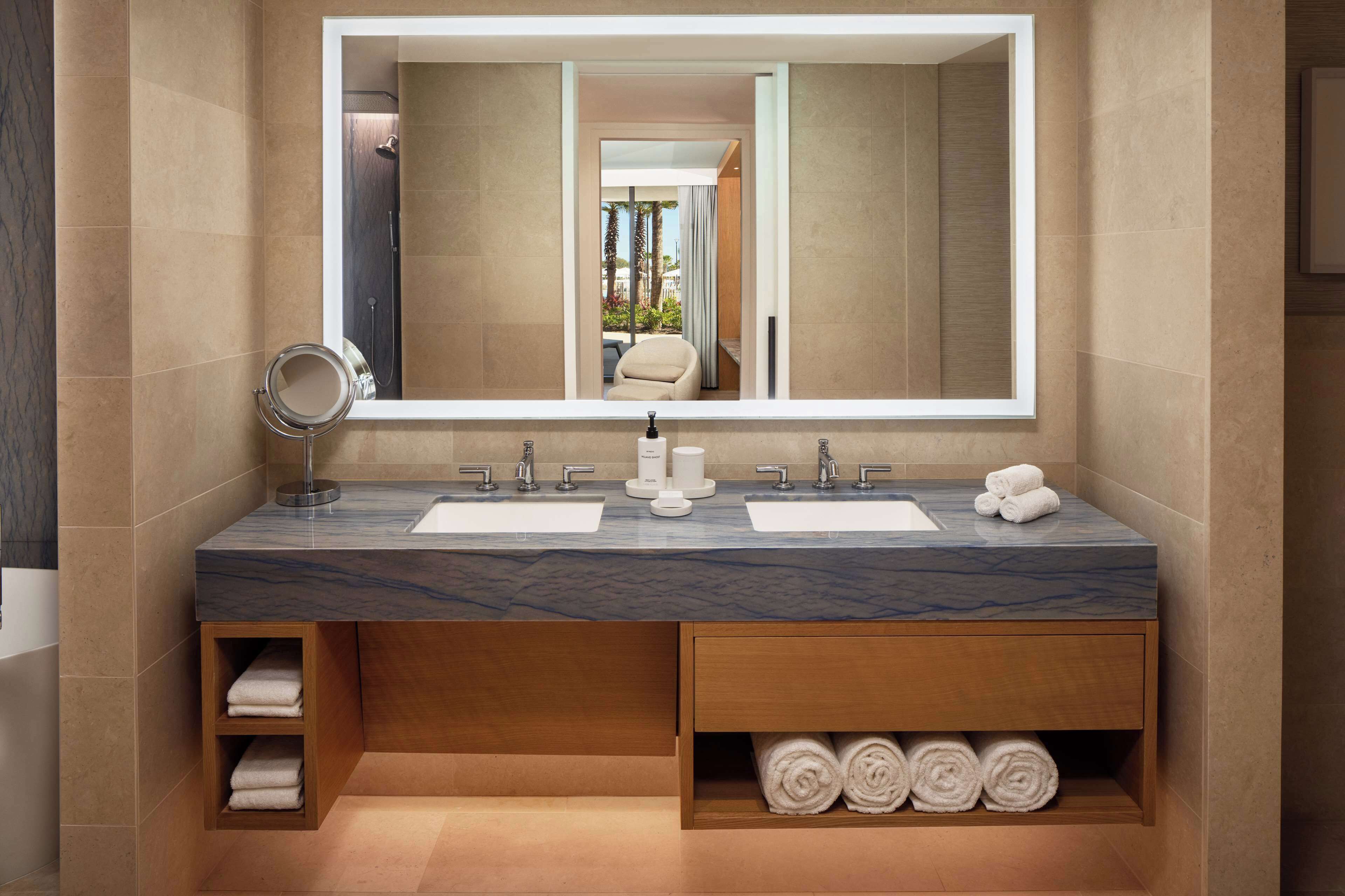 Un baño moderno con dos lavamanos, un espejo grande y estantes empotrados para toallas.