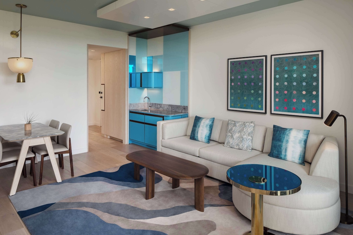 A modern living room with a sofa, coffee table, and dining area.