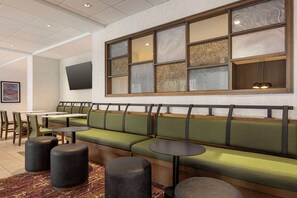 A modern restaurant with a long green cushioned bench, black stools, and a flat-screen TV mounted on the wall. - Hampton Inn Stockton, Ca (Stockton)