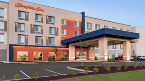 A Hampton Inn hotel with a modern facade, multiple windows, and a parking lot.