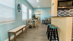 A kitchen with a built-in microwave, a dining area with a bench, and a bar area with stools.