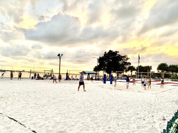 A beach volleyball court with players and spectators.