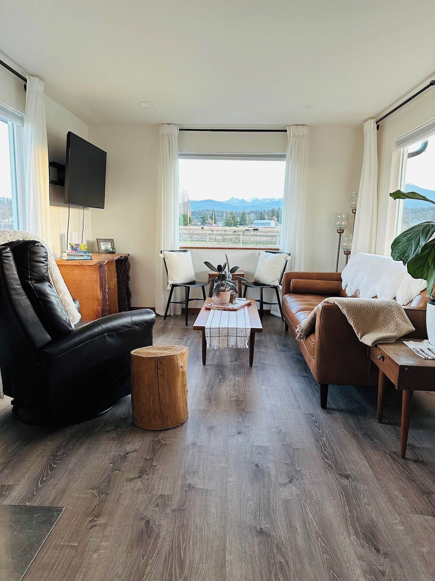 A modern living room with a leather sofa, a wooden coffee table, and a TV mounted on the wall.