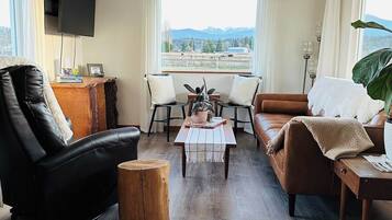 A modern living room with a leather sofa, a wooden coffee table, and a TV mounted on the wall.