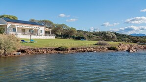 Ein Haus mit Pool, einer Terrasse mit Stühlen und Blick auf das Wasser.