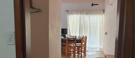 Un pasillo que conduce a un comedor con ventilador de techo, una mesa y sillas.