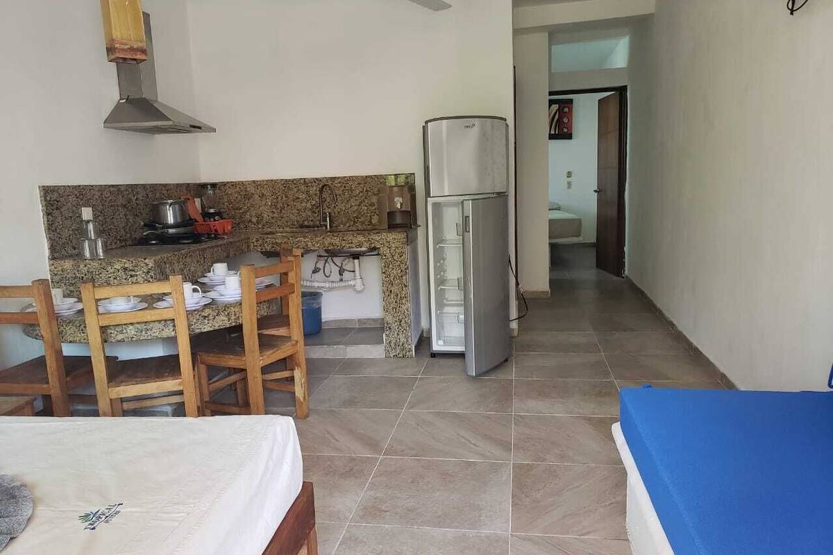 A compact kitchen with a gas stove, sink, and a refrigerator. There is a dining area with a table and chairs.