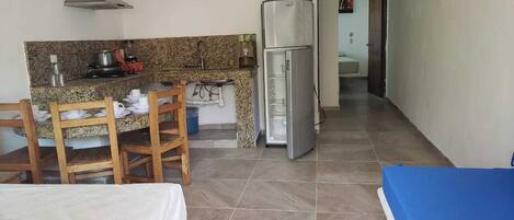 A compact kitchen with a gas stove, sink, and a refrigerator. There is a dining area with a table and chairs.