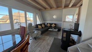 A modern living room with a black sofa, a glass coffee table, and a wood-burning stove. - 5 star hotel according to DTV - pure luxury, only 200m from the beach - WLAN free of charge (Dranske)