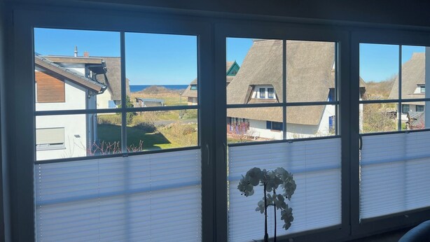 A room with a large window overlooking a coastal village with traditional houses and a clear sky. - 5 star hotel according to DTV - pure luxury, only 200m from the beach - WLAN free of charge (Dranske)