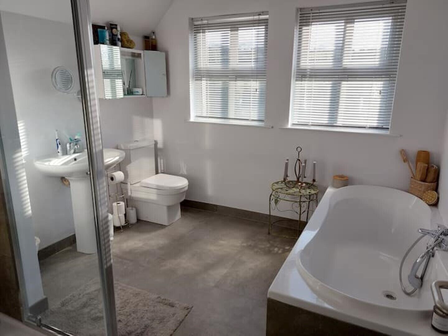 Une salle de bain moderne avec une baignoire, des toilettes, un lavabo et une petite table avec des bougies.