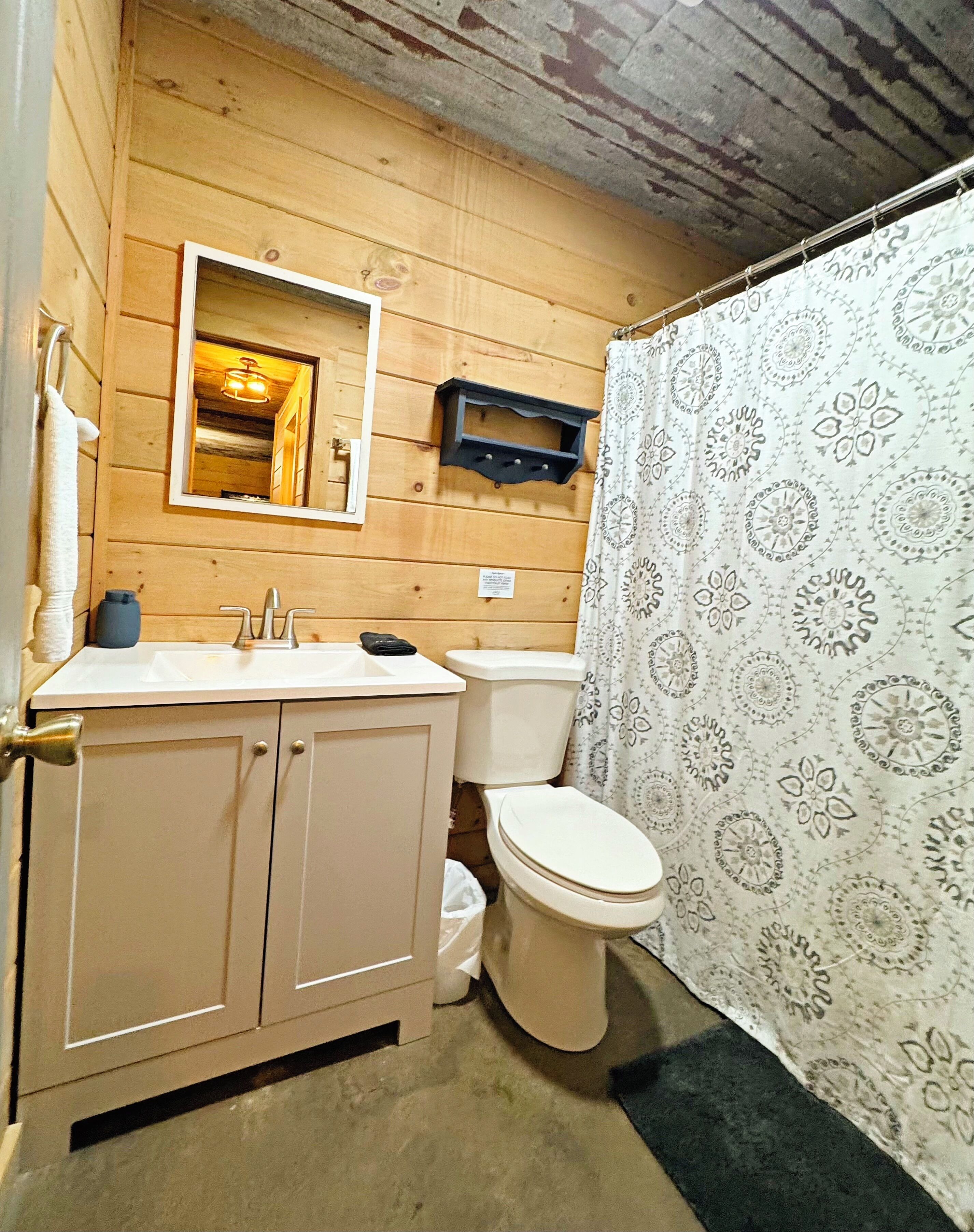 A wooden-paneled bathroom with a toilet, sink, and mirror.