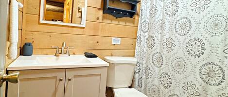 A wooden-paneled bathroom with a toilet, sink, and mirror.