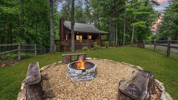 A cabin with a stone fire pit and a wooden deck.