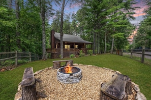 A cabin with a stone fire pit and a wooden deck.