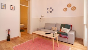 Un salón con sofá, mesa de centro, alfombra y una puerta que da a un baño.