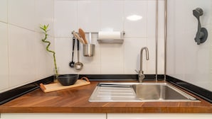 Una cocina moderna con un lavamanos de acero inoxidable, encimera de madera y una planta de bambú.