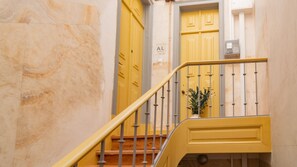 A staircase with a yellow handrail and metal balusters, leading to a door marked "AL".