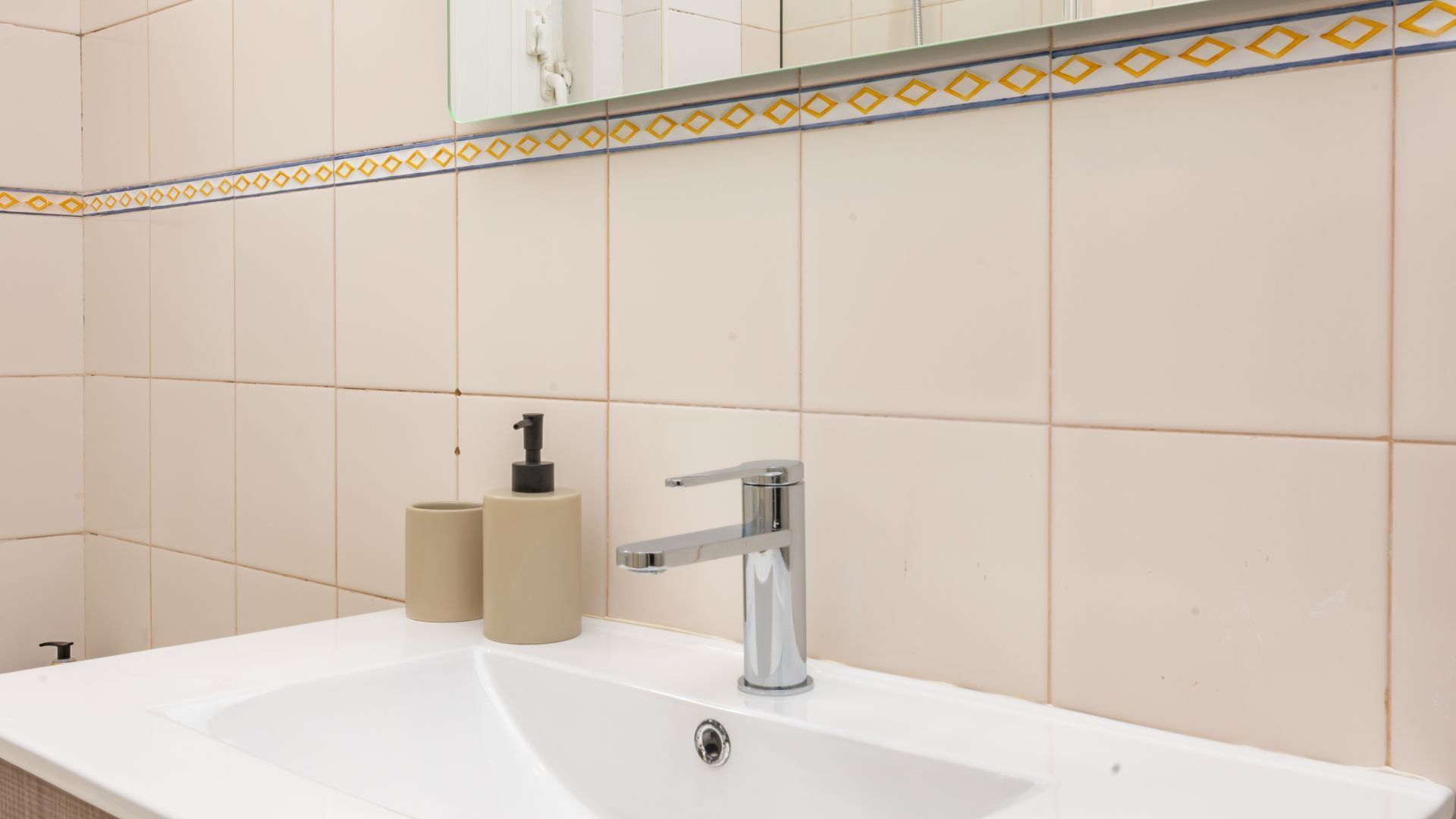 A bathroom with a white sink, a chrome faucet, and beige toilet paper rolls.
