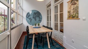 Ein Essbereich mit einem Holztisch, schwarzen Stühlen, einem blauen Teppich und einer Wandmalerei mit einer Weltkarte.
