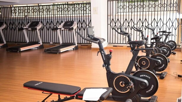 A gym with stationary bikes, treadmills, and a bench. - New Luxury Apartment very secure at State House Nairobi (kilimani)
