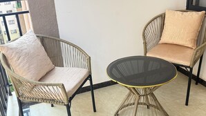 A balcony with wicker chairs and a glass table. - New Luxury Apartment very secure at State House Nairobi (kilimani)