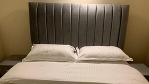 A bed with a padded headboard, two pillows, and a white bedspread. - New Luxury Apartment very secure at State House Nairobi (kilimani)