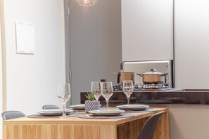 A modern kitchen with a dining table set for four, a gas stove, and a pot on the stove. - Apart no Mardisa Design por Carpediem (João Pessoa)